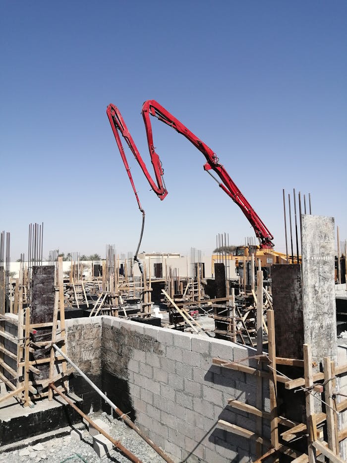 Concrete pump at a construction site under a clear sky in Al Dhaid, UAE. Urban development in progress.